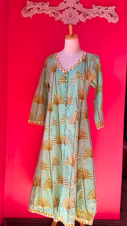 A light green and gold printed long kurta displayed on a dress form mannequin against a bright pink background.