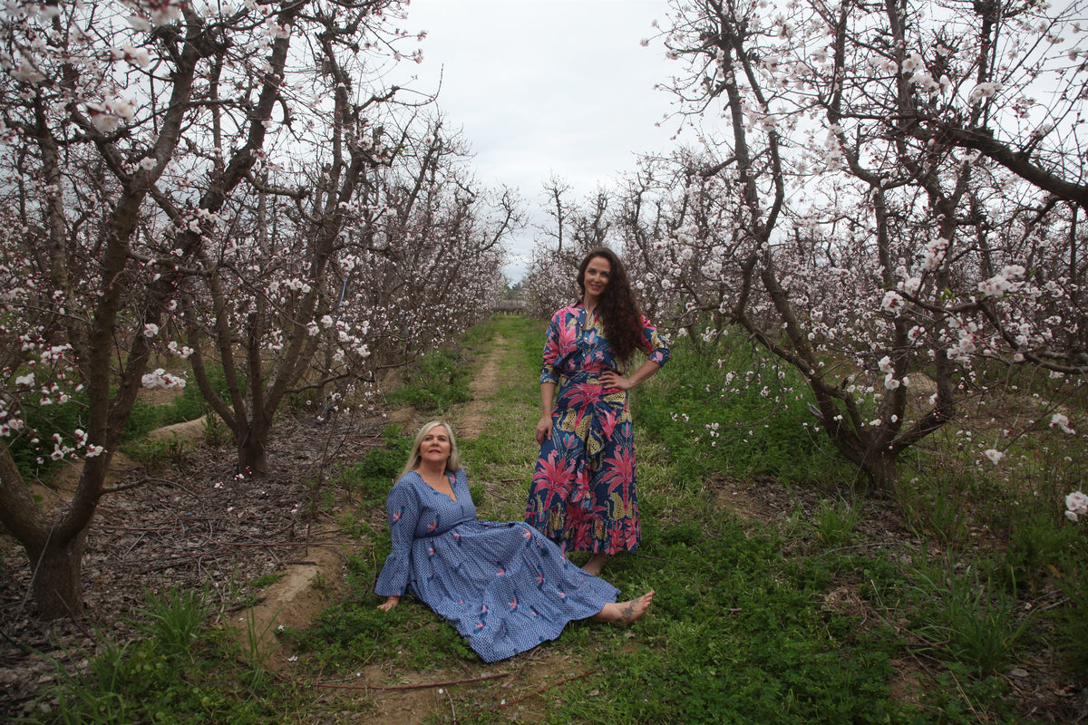 Tess and Sam of Gypsey Rose in colourful cotton dresses in a blossoming orchard