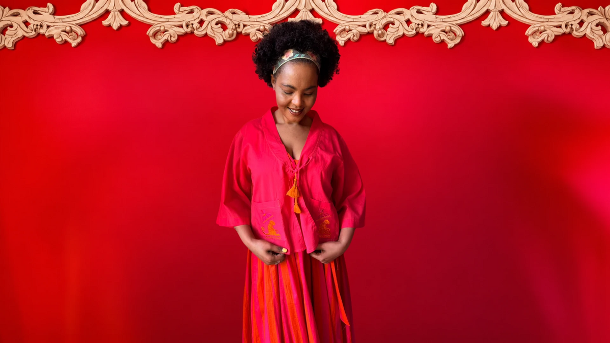 Model wearing the Gypsey Rose Kimmie Cropped Jacket in bright pink against a red wall