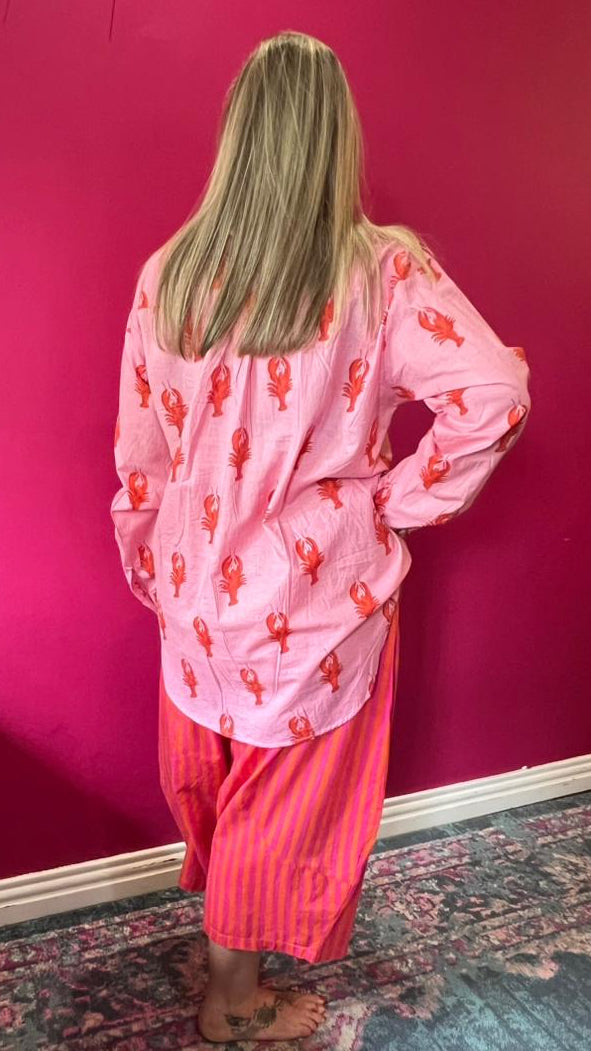 Person wearing pink pajamas with a pattern in a room with a pink wall.